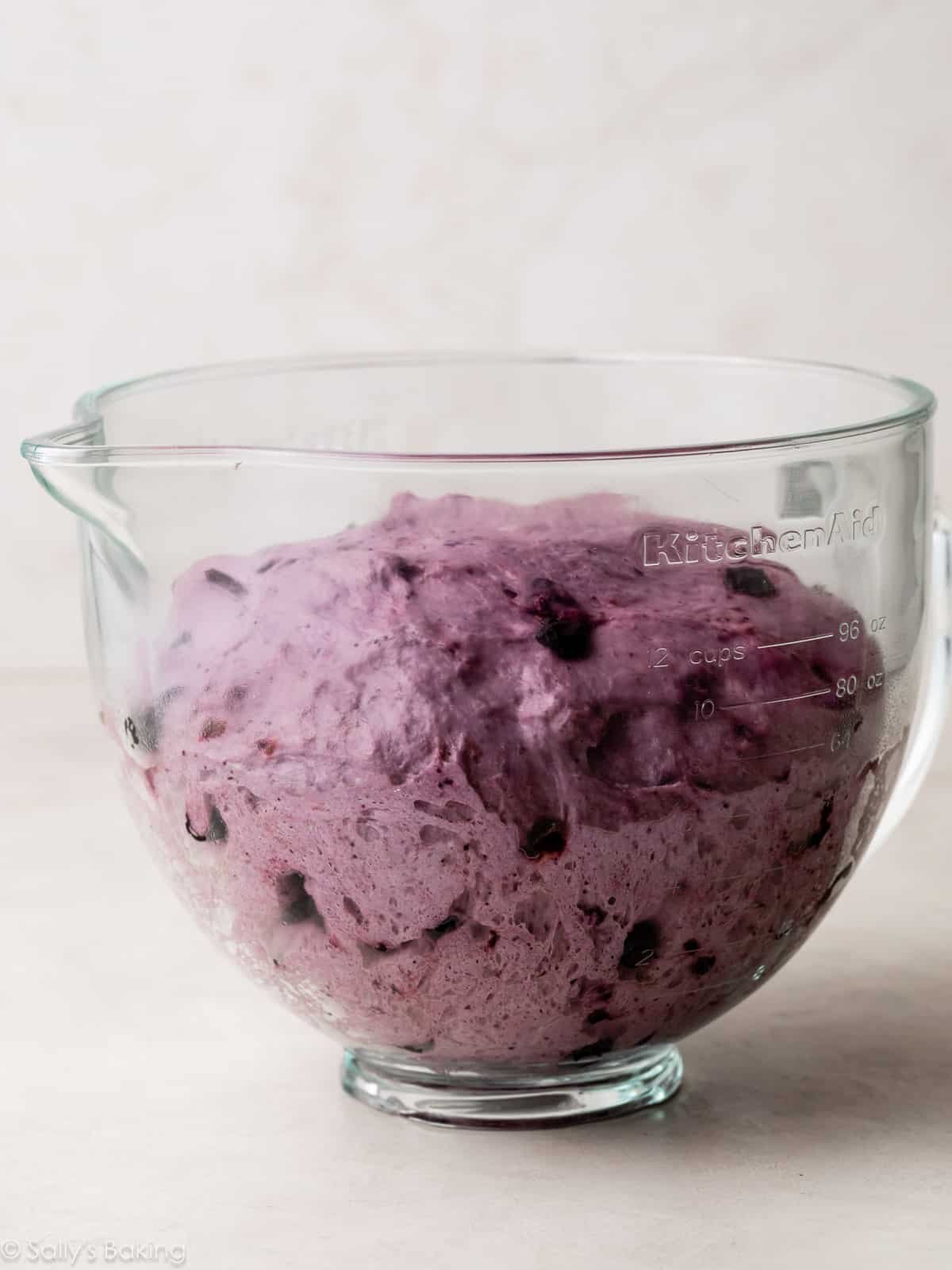 blueberry dough risen in glass bowl.